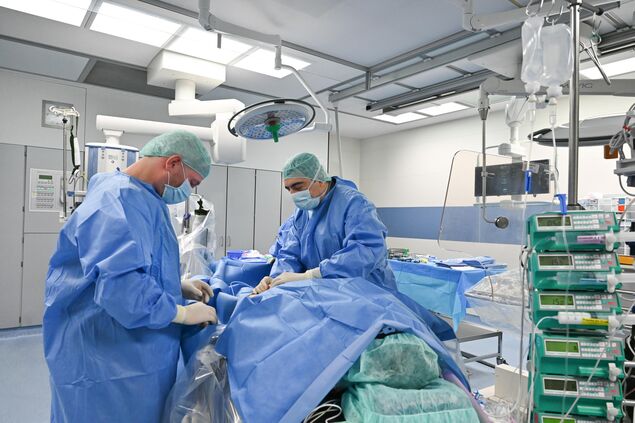 Zwei Chirurgen stehen sich gegenüber am Op Tisch und operieren