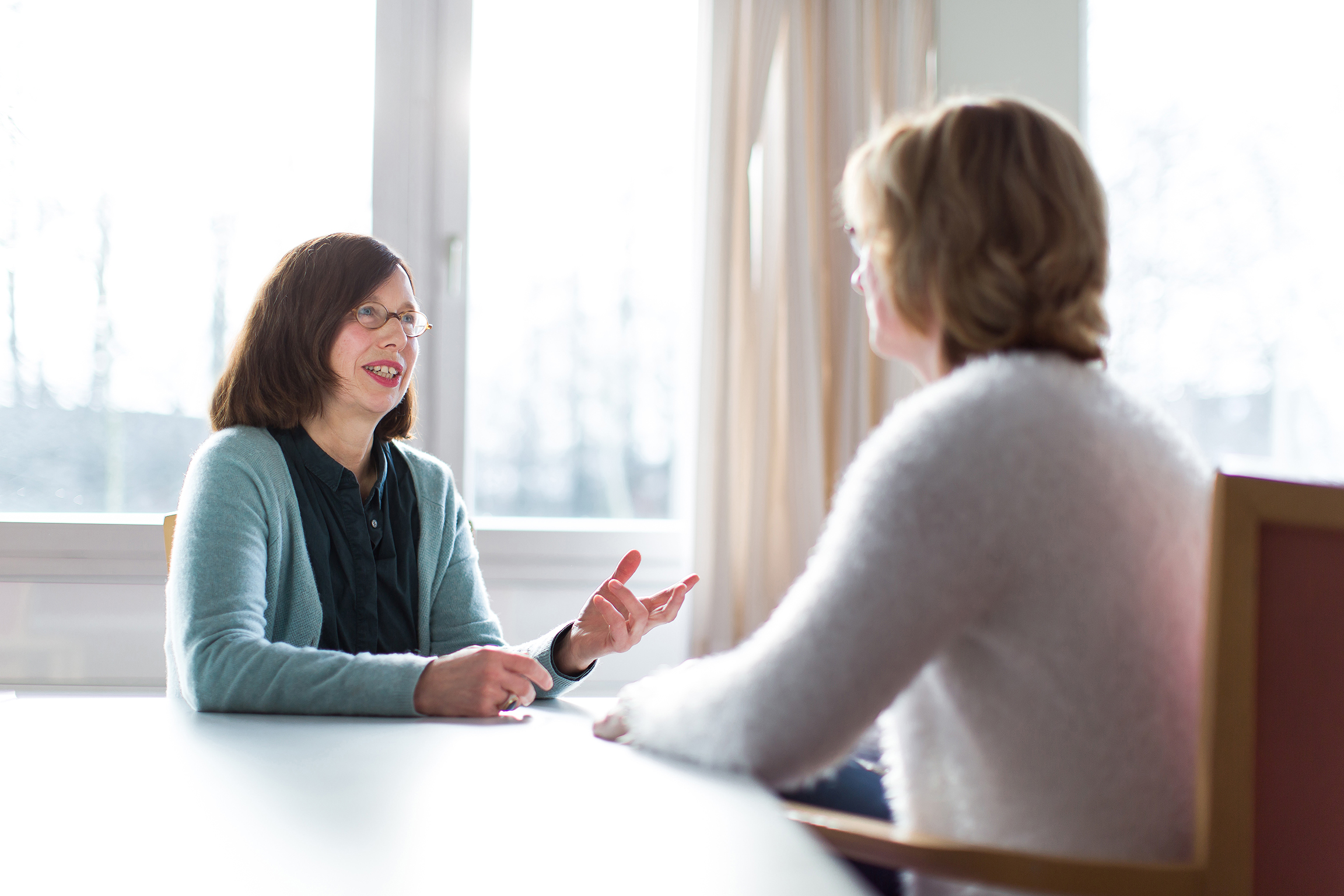 Zwei Frauen am Tisch in vertrautem Gespräch